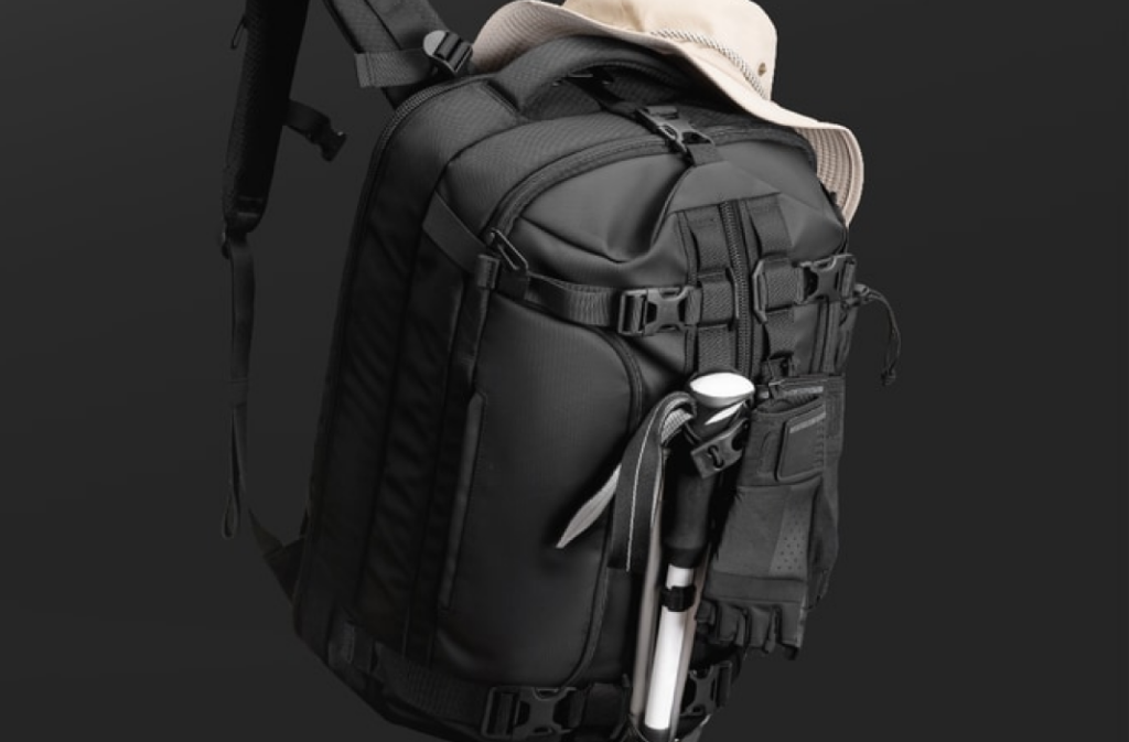 A multi-panel spec sheet titled 'KEY FEATURES AT A GLANCE' detailing the Cinomadist Motion A Backpack. It showcases its 28L structured capacity, center-line access, 17+ pocket organization, compression system, tech protection, and durable 1800D/1260D nylon fabrics.